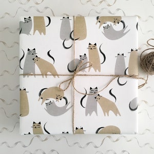 May include: White wrapping paper with a repeating pattern of grey and brown cats. The cats are in various poses, including cuddling and sleeping. The paper is tied with twine.