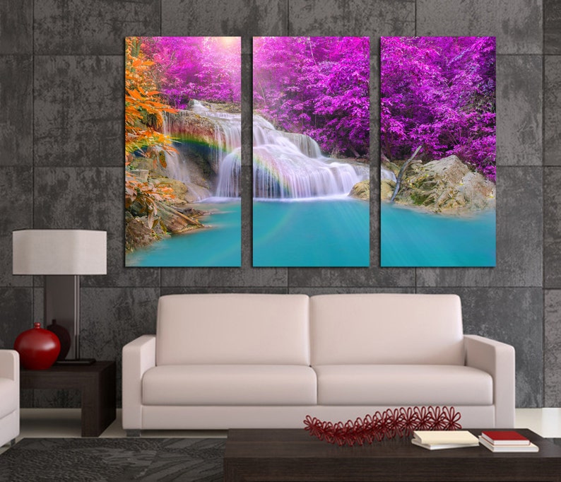 May include: A three-panel canvas print featuring a waterfall cascading through a lush forest with vibrant purple and orange foliage. The water is a bright turquoise blue and a rainbow is visible in the mist.