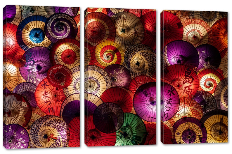 May include: A close-up of a wall covered in colorful Japanese paper umbrellas. The umbrellas are arranged in a random pattern and are all different sizes and shapes. Some of the umbrellas have Japanese characters written on them.