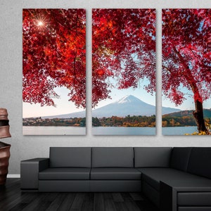 Peut inclure: Impression sur toile en trois parties représentant le Mont Fuji au Japon. L'œuvre présente des feuilles d'automne rouge vif encadrant la montagne et un lac serein. Le soleil transperce le feuillage, créant une ambiance chaleureuse.