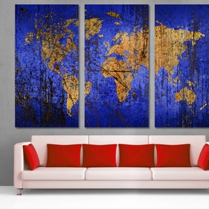 May include: A three-panel canvas wall art featuring a gold world map on a blue distressed background. The canvas is displayed above a white couch with red throw pillows.