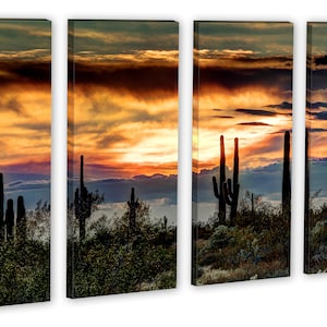 May include: A four-panel canvas print depicting a desert sunset. Silhouetted saguaro cacti stand in the foreground against a backdrop of a vibrant orange and yellow sky with dramatic cloud formations. The artwork evokes a sense of the American Southwest.