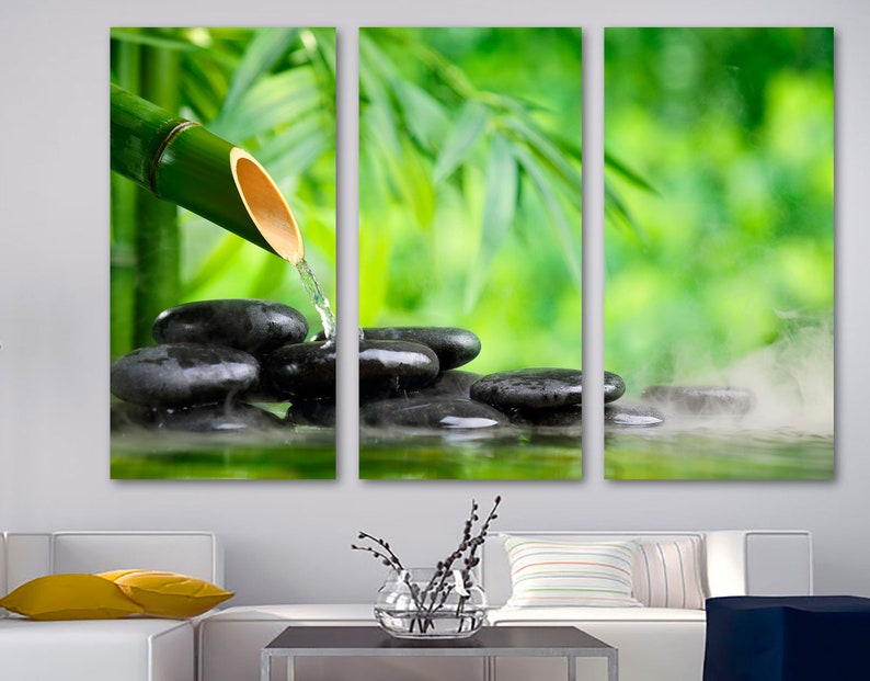 May include: A three-panel canvas print featuring a bamboo shoot pouring water onto smooth black stones in a tranquil setting. The background is a blurred image of green leaves.