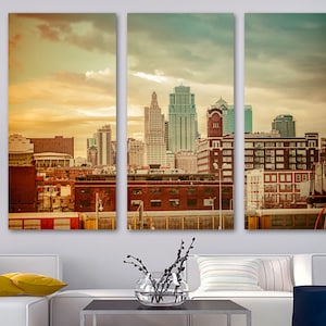 May include: A three-panel canvas print depicting a cityscape with a vintage effect. The image shows a skyline of tall buildings and skyscrapers, with a mix of brick and modern architecture under a cloudy sky. The colour scheme is warm, with golden and brown tones.