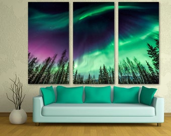 May include: A three-panel canvas print depicting a vibrant green and purple aurora borealis over a dark forest silhouette. The aurora is a natural light display in the sky, often seen in the northern hemisphere.