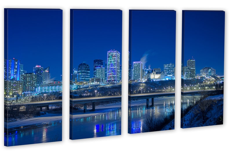 May include: A four-panel canvas print of a city skyline at night. Buildings with illuminated windows and lights are reflected in the water below. The sky is a deep blue, and the scene evokes a sense of urban life.
