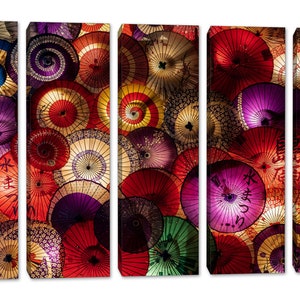 May include: A multi-panel wall art print featuring a close-up of colorful Japanese paper umbrellas. The umbrellas are arranged in a circular pattern, with the handles facing outward. The umbrellas are made of a thin, translucent paper, and they are decorated with a variety of patterns and designs. The colors of the umbrellas are vibrant and eye-catching, and they create a sense of movement and energy.