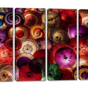 May include: A colorful wall art print featuring a close-up of a collection of Japanese paper umbrellas. The umbrellas are arranged in a random pattern and feature various colors, including red, purple, green, and yellow. The umbrellas have intricate designs and patterns, including floral motifs and Japanese characters.