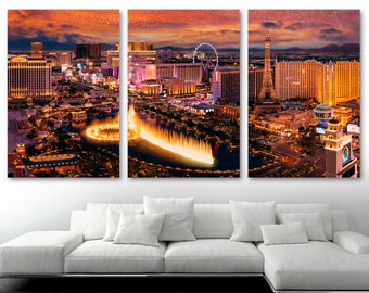 May include: An aerial view of the Las Vegas skyline at sunset, featuring the Bellagio fountains, the Eiffel Tower replica, and the High Roller observation wheel. The city lights are illuminated against a vibrant orange and pink sky.