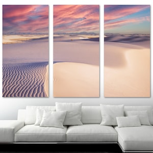 May include: A three-panel canvas print featuring a panoramic view of white sand dunes with a pink and blue sky at sunset. The dunes are textured and create a sense of depth and movement.