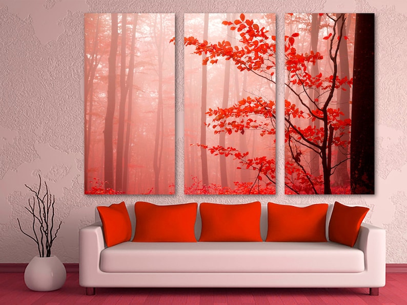 Op de afbeelding: Een driedelig canvas wandkunstprint met een mistige bos sc&egrave;ne met rode bladeren. De bladeren zijn op de voorgrond en de bomen op de achtergrond. De kleuren zijn gedempt en het algehele effect is kalmerend.