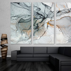 May include: Abstract art print in shades of gray, black, and gold. The print is divided into three panels, each featuring swirling, organic shapes.