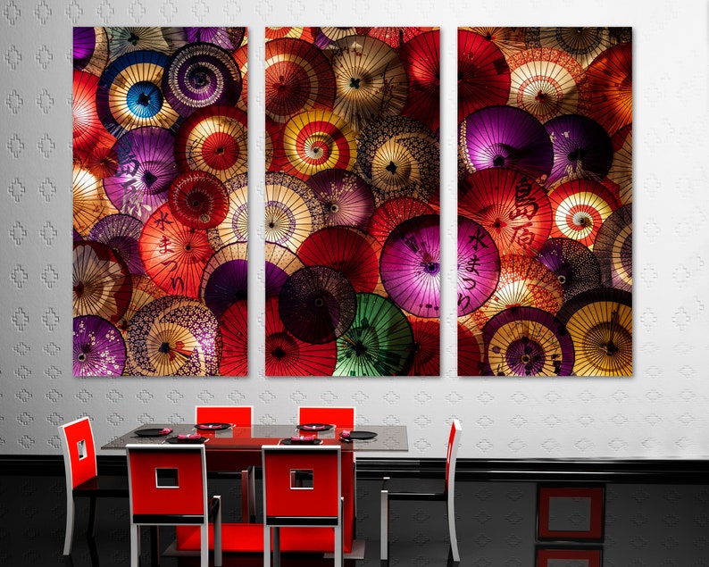 May include: A set of three colorful canvas prints featuring a close-up of a collection of Japanese umbrellas with various patterns and designs. The umbrellas are arranged in a circular pattern and are illuminated with warm lighting.