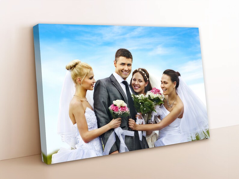 May include: A group of four people in wedding attire pose for a photo. The groom stands in the center, holding a bouquet of pink flowers. The two brides stand on either side of him, each holding a bouquet of white and pink flowers. The fourth person is a bridesmaid, standing behind the brides, with a white veil and a bouquet of pink and white flowers.