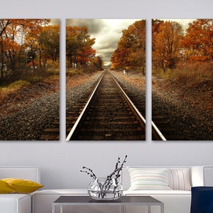 May include: A three-panel canvas print featuring a scenic view of a railroad track leading into a forest with autumn foliage. The trees are a mix of orange, yellow, and red.