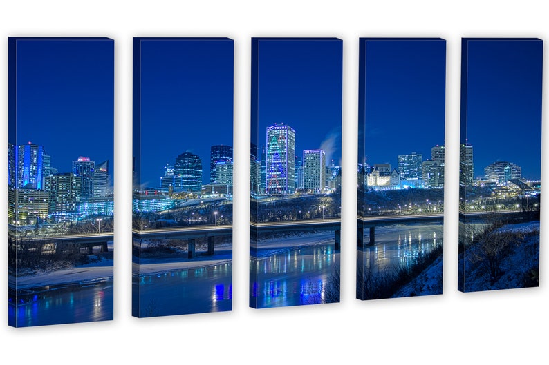 May include: A five-panel canvas print of a city skyline at night. The buildings are illuminated with various colors, reflecting in the water below. A bridge crosses the water, and the sky is a deep blue.
