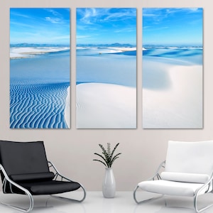 May include: A three-panel canvas print featuring a panoramic view of white sand dunes under a bright blue sky. The dunes are textured and create a sense of depth and movement. The print is perfect for adding a touch of nature to any room.