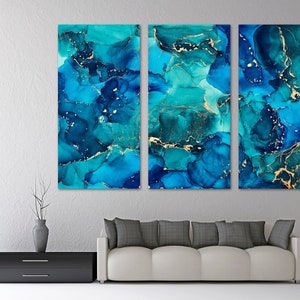 May include: Abstract art print featuring a blue and gold color scheme. The print is divided into three panels, each with a unique swirling pattern of blue and gold paint.