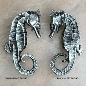 May include: Two silver seahorse sculptures, one facing right and one facing left. The sculptures are detailed and have a textured finish. The seahorses are labeled "DHK90 - RIGHT FACING" and "DHK91 - LEFT FACING".