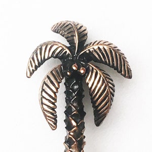 May include: A bronze palm tree door pull with a detailed textured trunk and leaves.