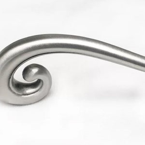 May include: A brushed nickel cabinet door pull with a curved design and a rounded end.