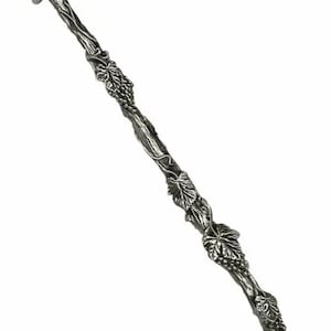May include: A silver-colored wand with a detailed design of vines, leaves, and grape clusters. The wand has a textured, rustic appearance, and a handle at the top. The overall design suggests a natural, botanical theme.