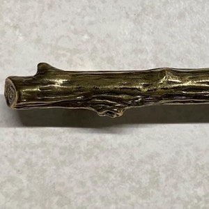 May include: A gold-toned metal cabinet pull shaped like a branch of a tree.