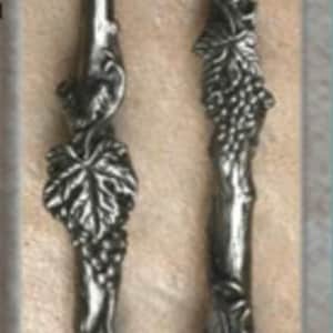 May include: Two silver grapevine handles with a 13 inch length and 10 inch center to center spacing. The handles are made of metal and have a detailed grapevine design. The text "DHP40 Grape Vine Handle 13"L/10" cc (left)" is at the top of the image. The text "DHP41 Grape Vine Handle 13"L/10" cc (right)" is at the bottom of the image.