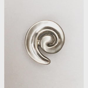 May include: A shiny, silver-colored spiral-shaped object. The design features a smooth, curved form, reminiscent of a nautilus shell. The object is set against a plain, light background.
