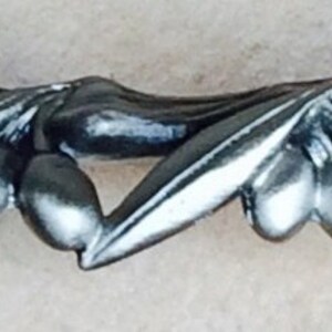 May include: Silver-toned metal olive branch drawer pull with a detailed design. The pull features multiple leaves and olives.