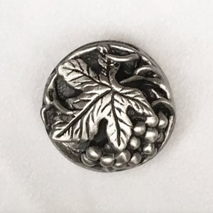 May include: A silver-toned metal button with a grapevine design. The button features a detailed grape leaf and a cluster of grapes.