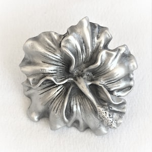 May include: A silver pewter hibiscus flower charm. The flower is detailed with realistic petals and a center stamen.
