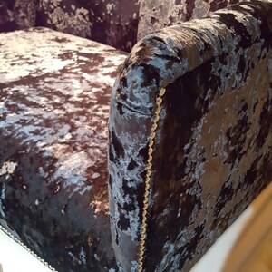 May include: A black and silver velvet sofa with a tufted back and gold trim. The sofa has a contemporary design and is upholstered in a luxurious fabric.