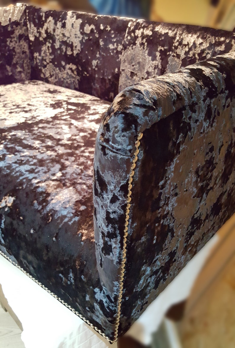 May include: A black and silver velvet sofa with a tufted back and gold trim. The sofa has a contemporary design and is upholstered in a luxurious fabric.