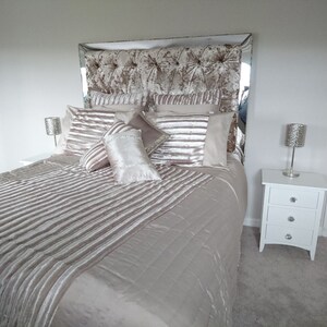 This picture shows a diamond tufted/chesterfield style headboard which is covered in Cristina Marrone Lustro Crushed Velvet in a champagne gold colour. The headboard also has a mirror frame and crystal buttons.