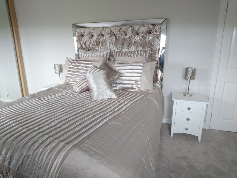 This picture shows a diamond tufted/chesterfield style headboard which is covered in Cristina Marrone Lustro Crushed Velvet in a champagne gold colour. The headboard also has a mirror frame and crystal buttons.