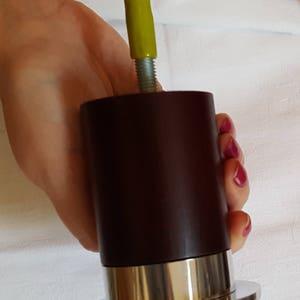 May include: A dark brown wooden furniture leg with a silver metal base and a yellow plastic cap on top.