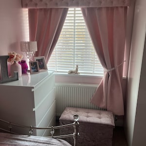 This is a pink and white bedroom with a pink velvet, chesterfield style box pelmet with matching curtains.
