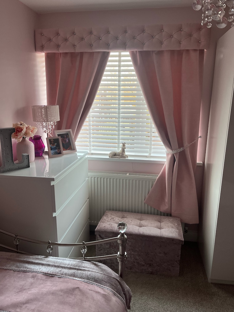 This is a pink and white bedroom with a pink velvet, chesterfield style box pelmet with matching curtains.