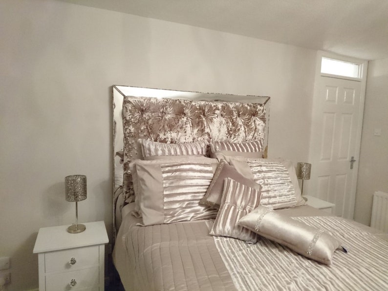 This picture shows a diamond tufted/chesterfield style headboard which is covered in Cristina Marrone Lustro Crushed Velvet in a champagne gold colour. The headboard also has a mirror frame and crystal buttons.