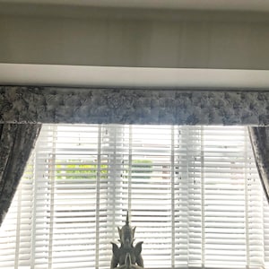 This picture shows a dark gray, crushed velvet, long chesterfield style box pelmet with crystal buttons.  There are also matching lined curtains.