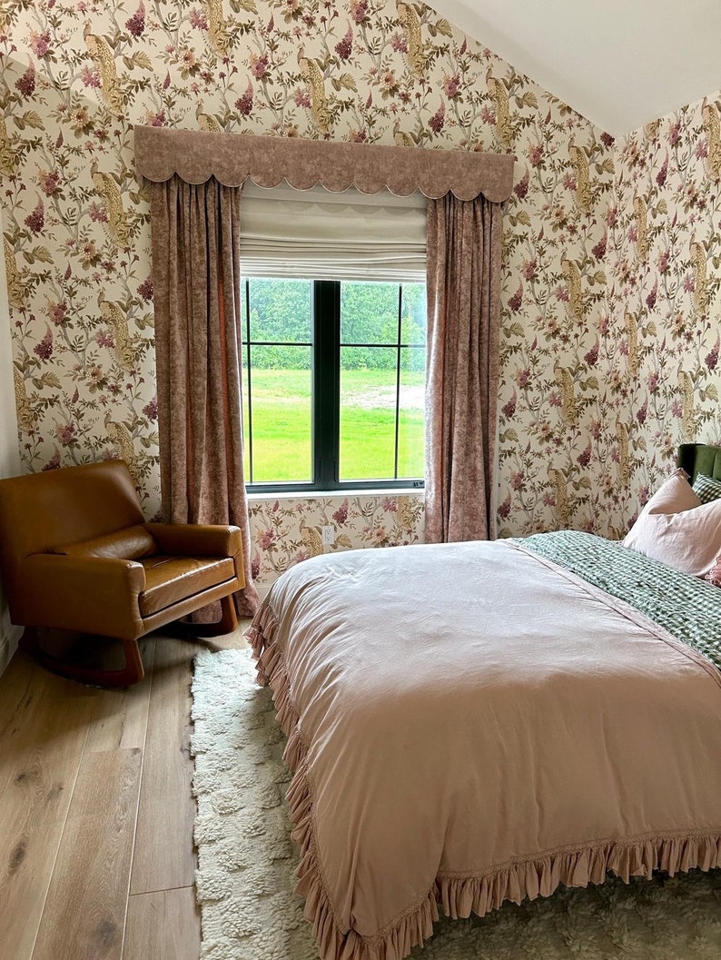 This picture shows a loft bedroom with a neutral coloured bedroom.  

There is a large window which has a scallop bottom pelmet and matching floor length lined curtains.