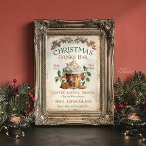Op de afbeelding: Een rechthoekige print in een sierlijke gouden lijst met de tekst CHRISTMAS DRINKS BAR, COFFEE, LATTE'S, SHAKES, HOT CHOCOLATE, Sugar, Spice, & Everything Nice. De afbeelding toont een mok met slagroom, hulst en koekjes.