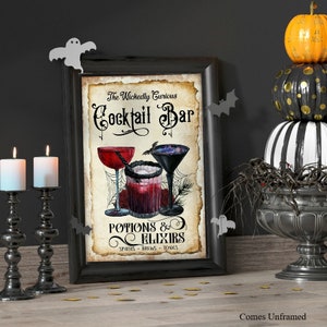 K&ouml;nnte beinhalten: Ein rechteckiger Wandkunstdruck in einem schwarzen Rahmen mit dem Text The Wickedly Curious Cocktail Bar Potions & Elixirs Spirits Brews Tonics. Die Illustration zeigt drei Cocktailgl&auml;ser mit roten und dunklen Fl&uuml;ssigkeiten, Spinnweben und Rosen.