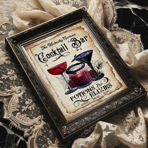 K&ouml;nnte beinhalten: Ein gerahmter Kunstdruck mit der Aufschrift The Wickedly Curious Cocktail Bar Potions & Elixirs Spirits Brews Tonics. Die Illustration zeigt ein rotes Cocktailglas, ein dunkles Glas mit schwarzem Rand und ein schwarzes Martiniglas mit Spinnweben.
