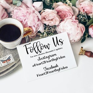 May include: A white rectangular card with black text reading Follow Us, For new releases, discounts & updates, Instagram @Heart2HeartbyHelen, and Facebook Heart2HeartbyHelen, positioned near a cup of black coffee and pink peony flowers.