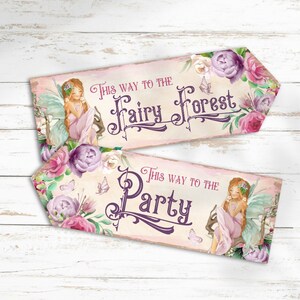 May include: Two arrow-shaped signs with a cream background, floral accents in pink and purple, and illustrations of a fairy with long hair and wings. The top sign reads "THIS WAY TO THE Fairy Forest" and the bottom sign reads "THIS WAY TO THE Party" in dark purple decorative lettering.
