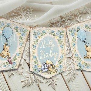 May include: A decorative pennant banner featuring Winnie the Pooh characters, blue floral borders, and the text Hello Baby. The design includes illustrations of Pooh holding a blue balloon and sitting with Eeyore, all set against a vintage-style background.