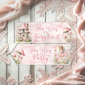 May include: Two rectangular signs with pointed ends featuring pink and white illustrations. The top sign displays a pink house and mushrooms with the text This Way to the Fairy Forest. The bottom sign shows a fairy and mushrooms with the text This Way to the Party.