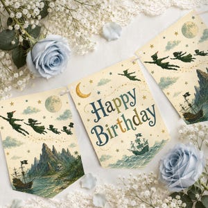 May include: A decorative banner featuring three cream-coloured pennants with Peter Pan illustrations. The centre pennant displays the text Happy Birthday in blue and gold lettering, surrounded by stars, a crescent moon, a pirate ship, and flying figures.